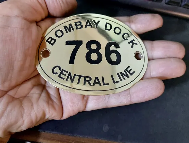 Oval polished brass plate with black-filled lettering and screw holes